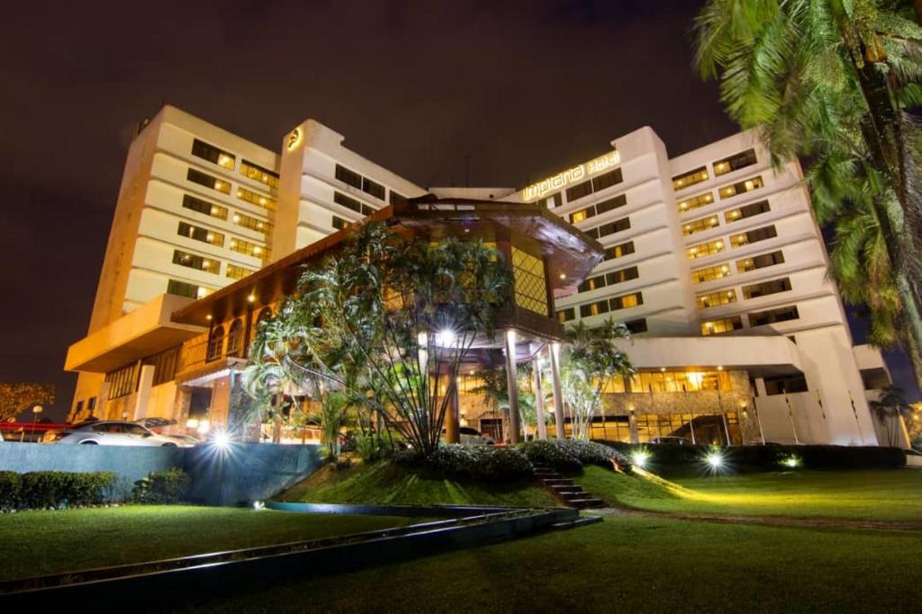 怡保怡保宴宾雅酒店的一座棕榈树在晚上前方的大建筑