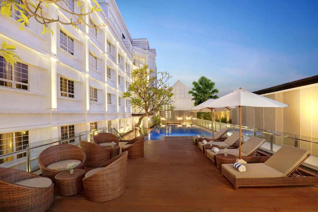 泗水Kokoon Hotel Surabaya的酒店配有桌椅和游泳池