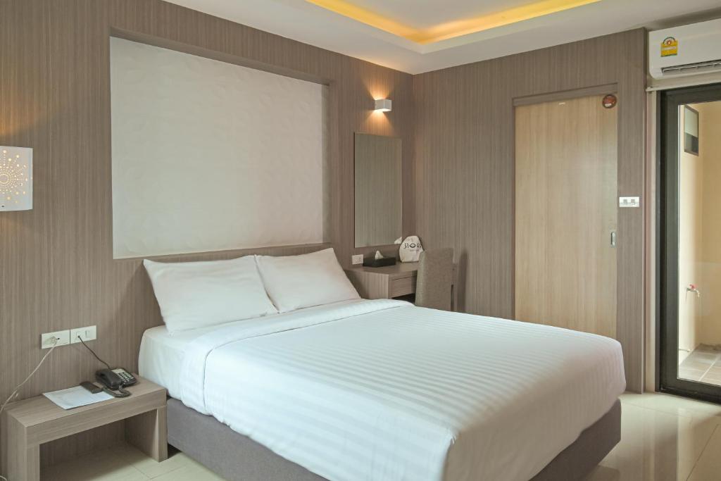 曼谷Sleep Hotel Bangkok的卧室配有一张白色的大床和两张桌子