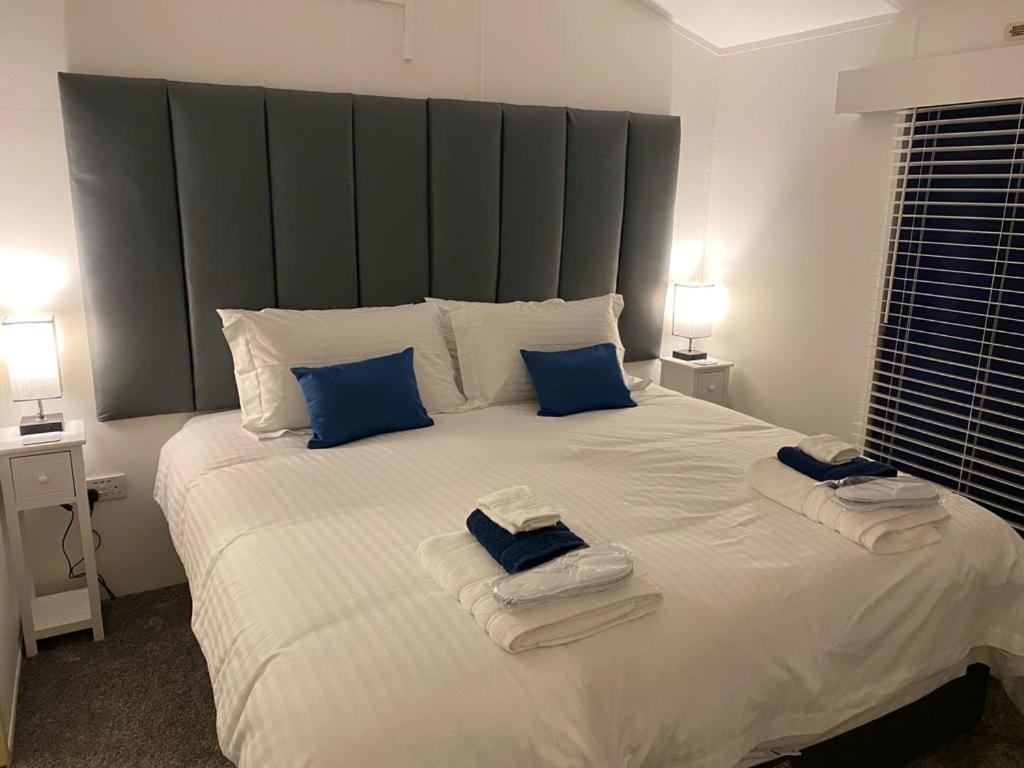 布里克瑟姆Loxley's Devon Lodge的卧室配有带蓝色枕头的大型白色床