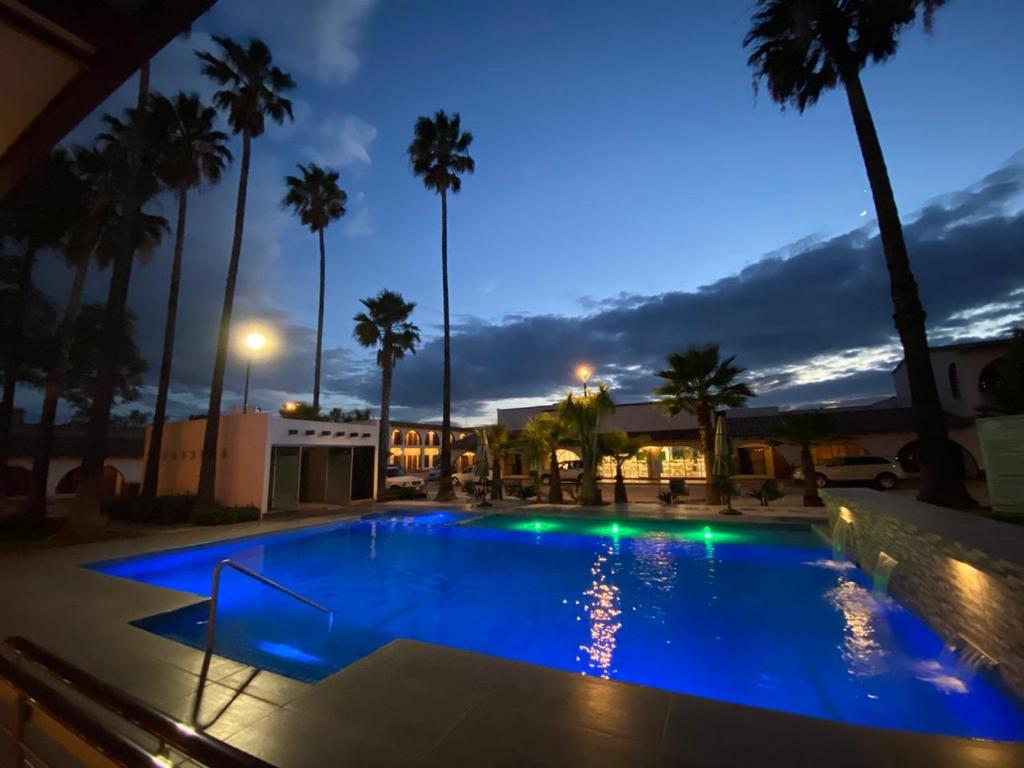 圣路易斯波托西Hotel Sand´s San Luis的棕榈树的夜间游泳池