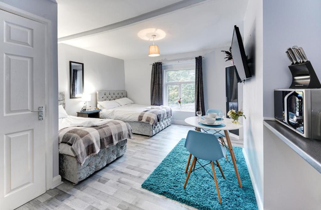 哈利法克斯Grey Stone Studio Apartments的一间卧室配有两张床和一张带蓝椅的桌子