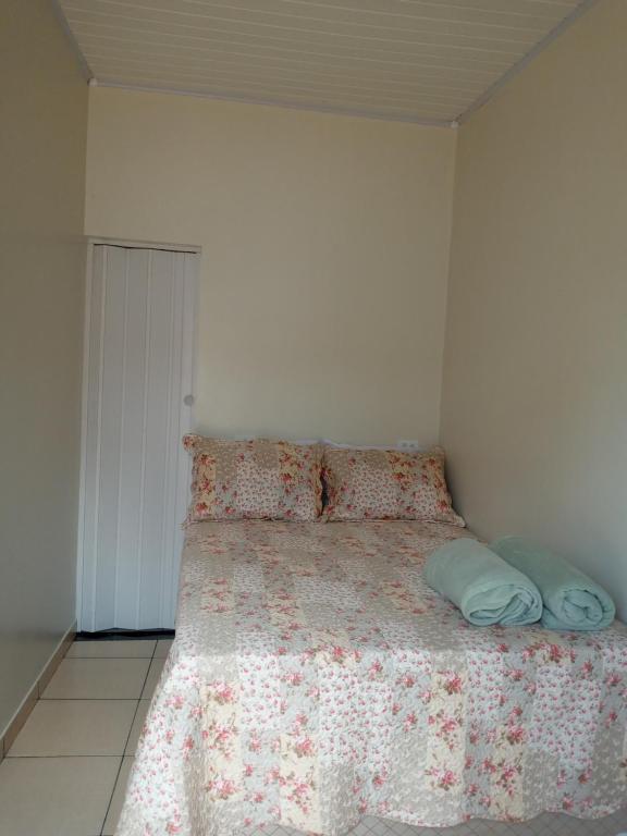 卡罗莱纳Quarto Suíte independente da casa com garagem的一间卧室配有一张带花卉床罩和枕头的床