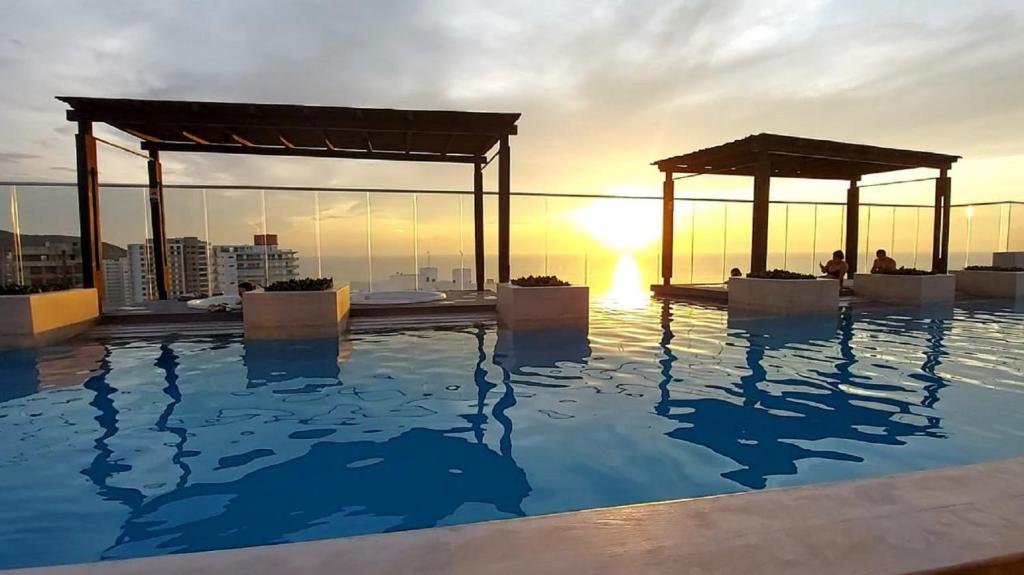 圣玛尔塔New Apartment Reserva del Mar 1421 Santa Marta ocean view的一座享有日落美景的建筑屋顶上的游泳池