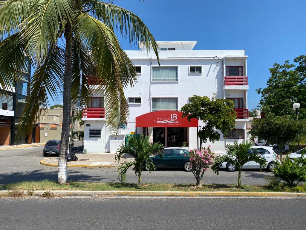 曼萨尼约Hotel LB的一座白色的建筑,有红色遮阳篷和棕榈树