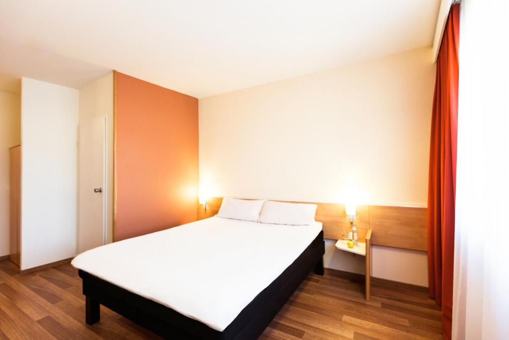 格拉茨宜必思格拉茨酒店的一间卧室配有一张带白色床单和橙色墙壁的床。
