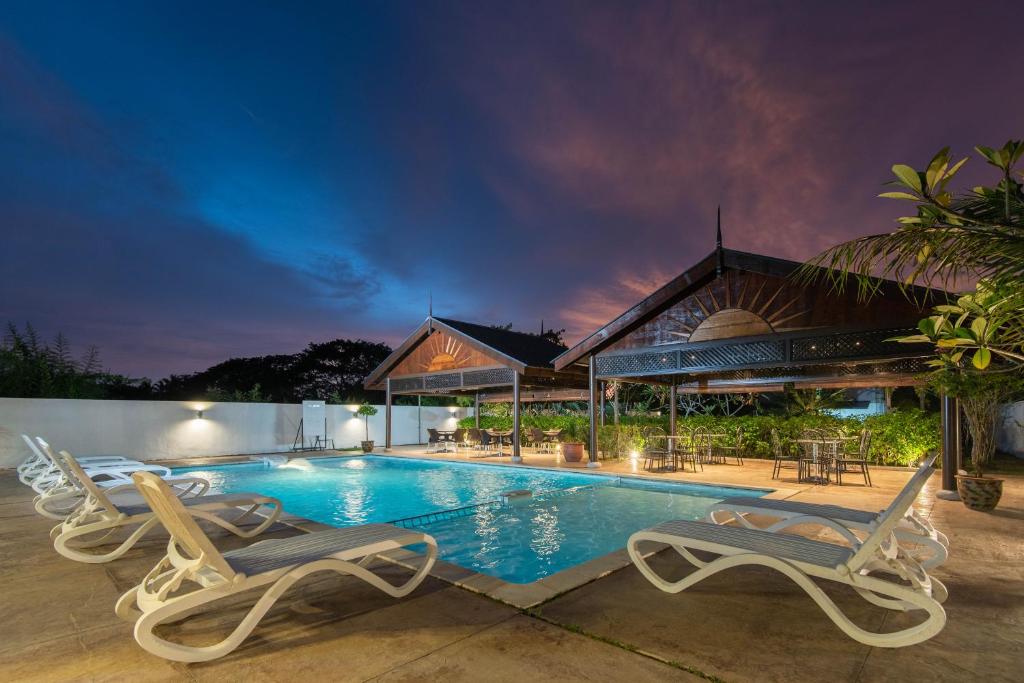 瓜埠Riverra Inn Langkawi的一个带两把椅子的游泳池以及一座房子