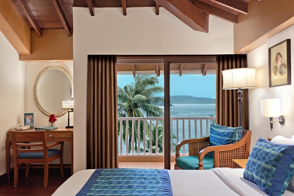 布莱尔港Welcomhotel by ITC Hotels, Bay Island, Port Blair的一间带一张床和一张书桌的卧室以及一个阳台