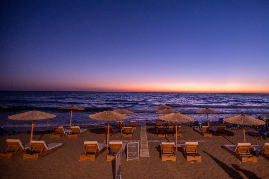 阿齐欧斯·贡多斯Romantic Palace Beach Apartments的海滩上设有椅子和遮阳伞,还有大海
