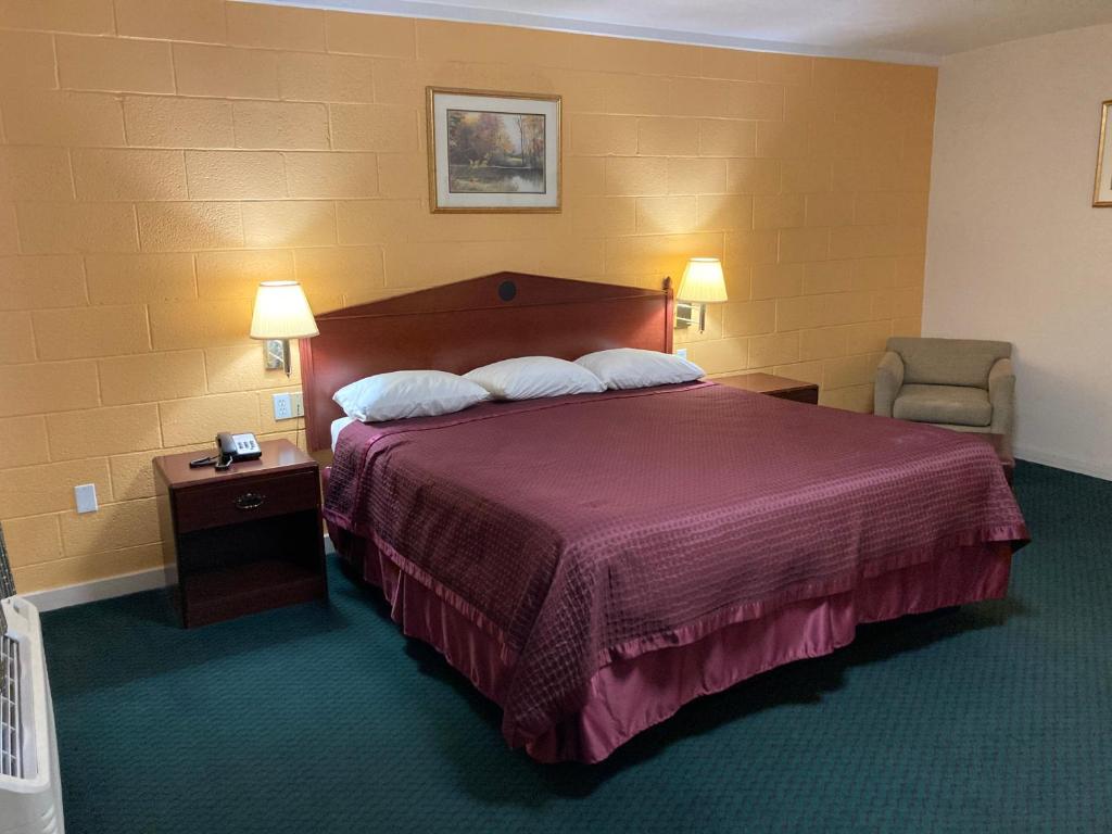 柴尔德里斯Childress Inn的配有一张床和一把椅子的酒店客房