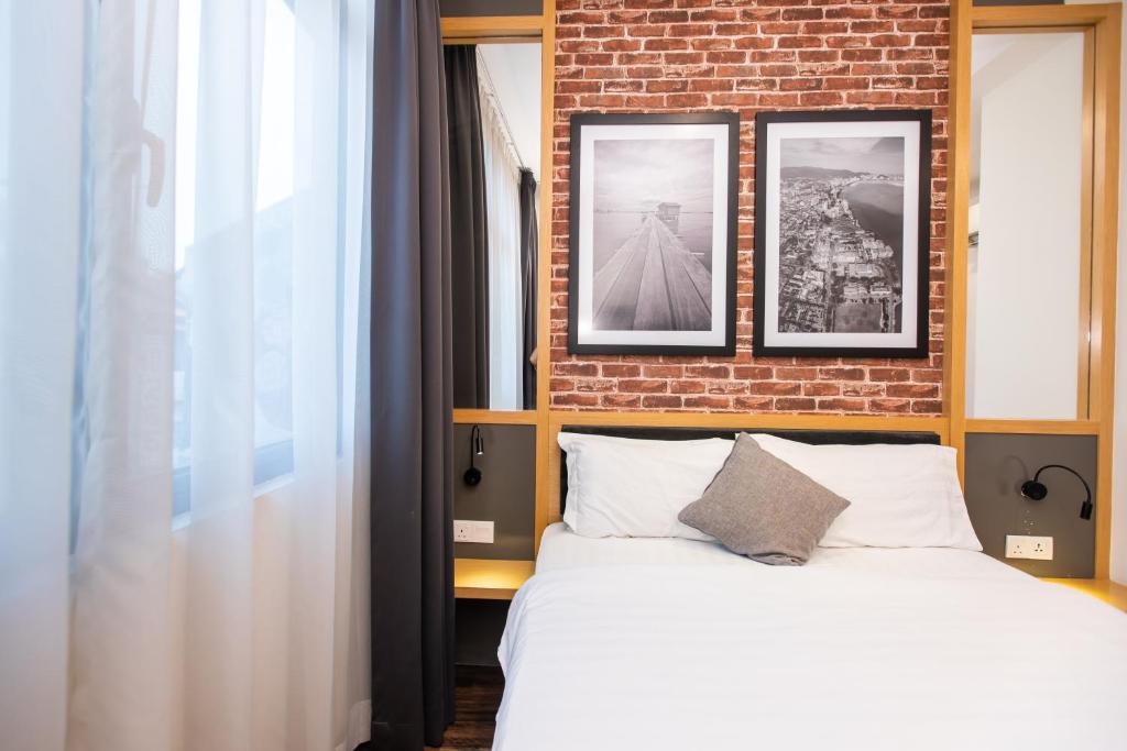 乔治市乙街酒店的一间卧室设有一张床和砖墙