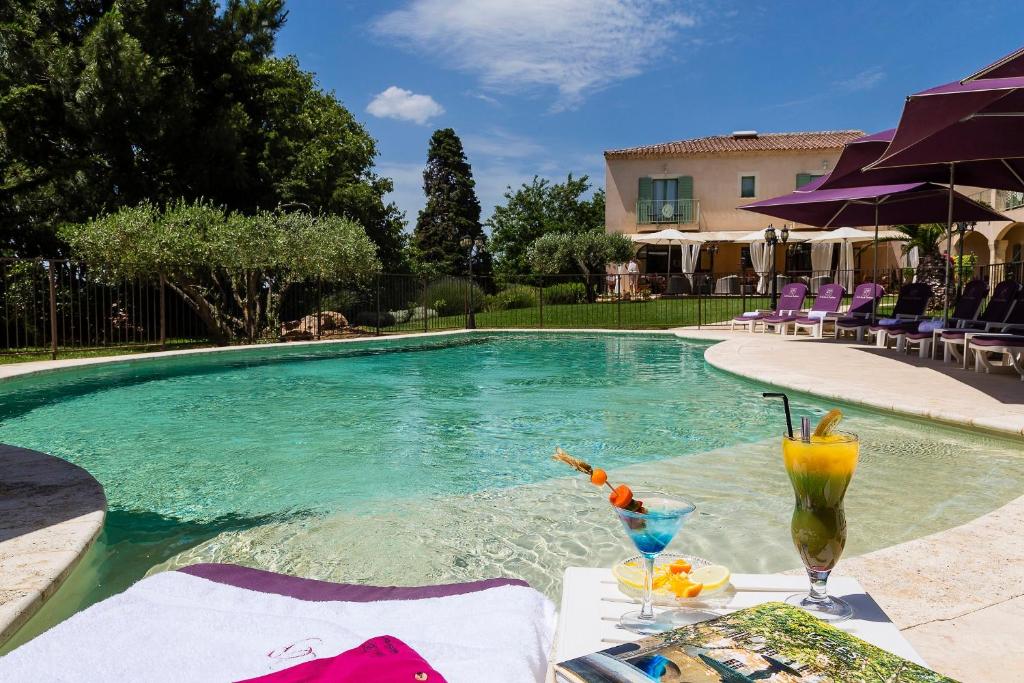 圣康坦拉波特里Hotel Restaurant Le Clos De Pradines的游泳池配有带饮品的桌子