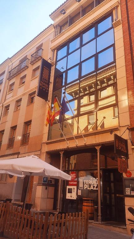 特鲁埃尔特鲁埃尔广场酒店的两面旗帜和一把伞在前面的建筑