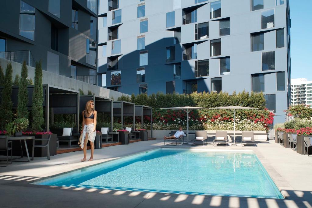 洛杉矶AKA West Hollywood, Serviced Apartment Residences的站在建筑物游泳池旁的女人