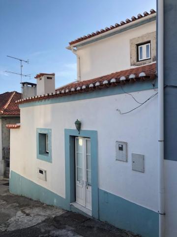 奥埃拉斯Typical small house near Lisbon的白色的建筑,边边有一扇蓝色的门