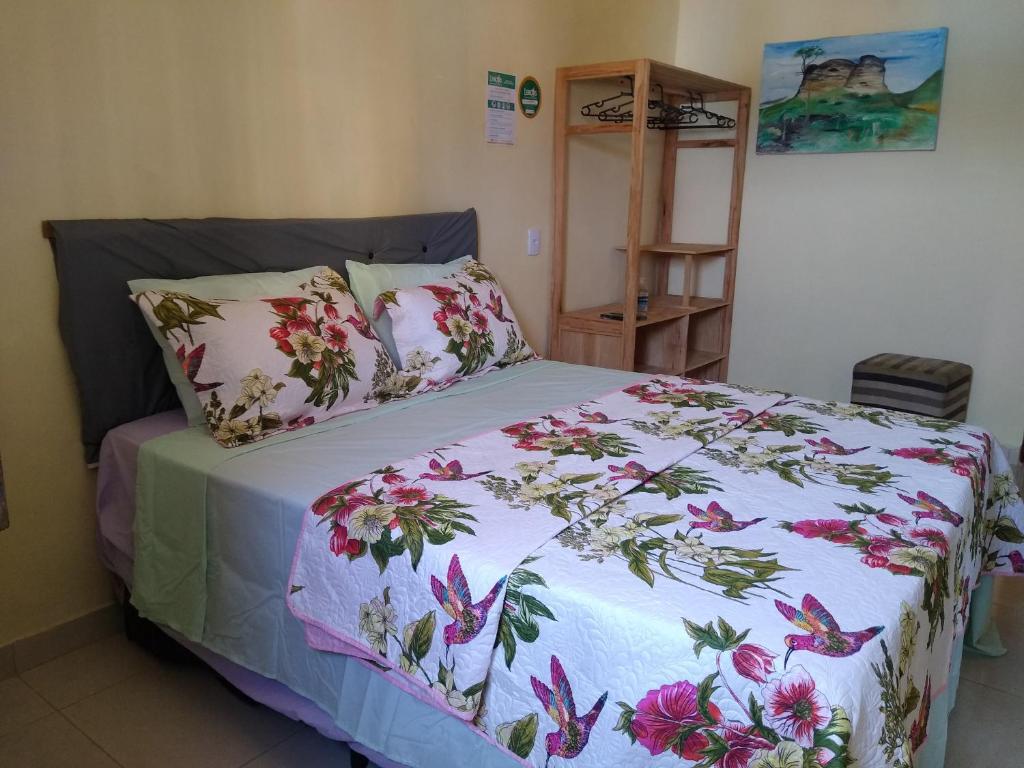 伦索伊斯Hospedaria Casa de Adriana的一间卧室配有一张带花卉床罩的床
