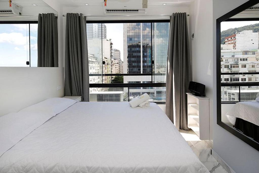 里约热内卢Studio moderno com vista privilegiada para a praia的卧室设有白色的床和大窗户