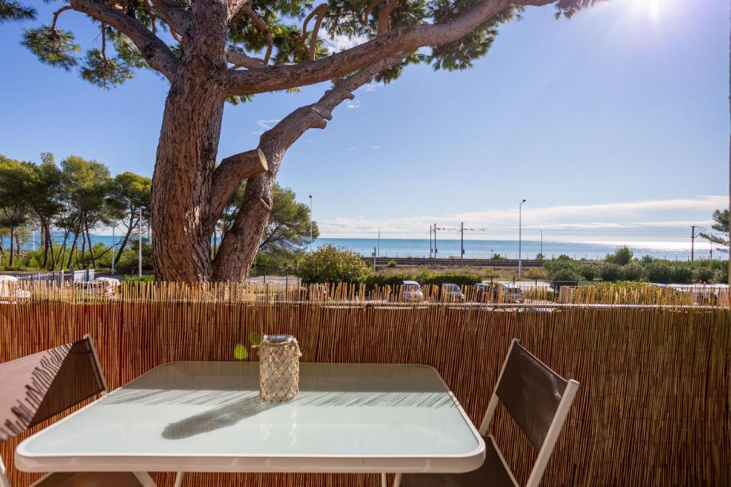 昂蒂布Appartement Marineland Sea View的桌椅,树和栅栏