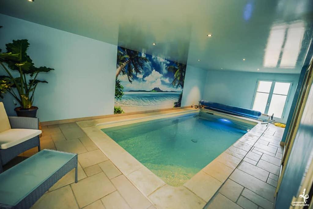 特鲁瓦Maison PISCINE INTERIEURE et GARAGE的蓝色墙壁的房间中的一个大型游泳池