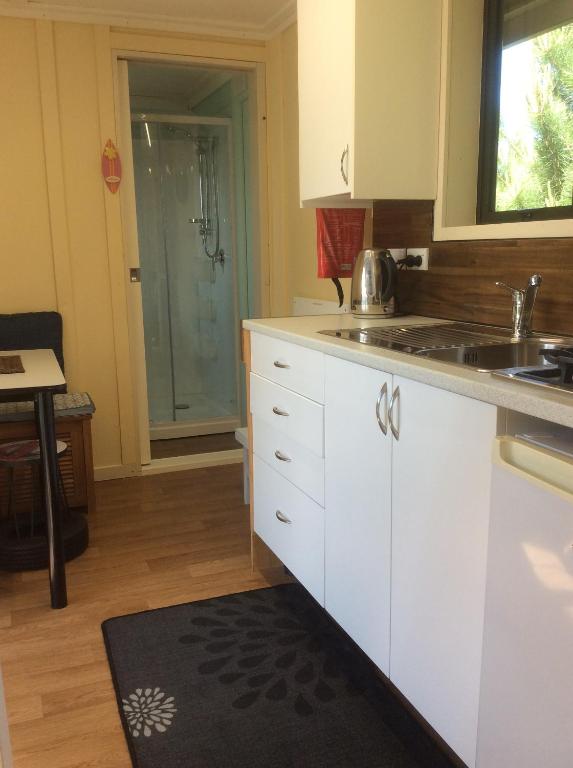 OxfordOxford Tiny House的厨房配有白色橱柜、水槽和淋浴。
