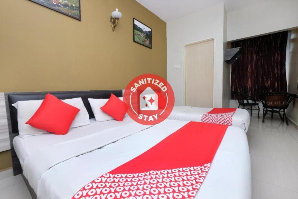 金马仑高原Super OYO 1152 Heaven Hill 2的配有红色和白色枕头的客房内的两张床