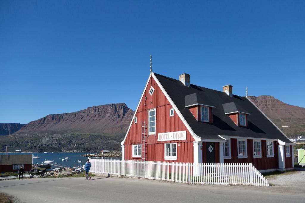 QeqertarsuaqHotel Disko Island的站在红房子前面的人