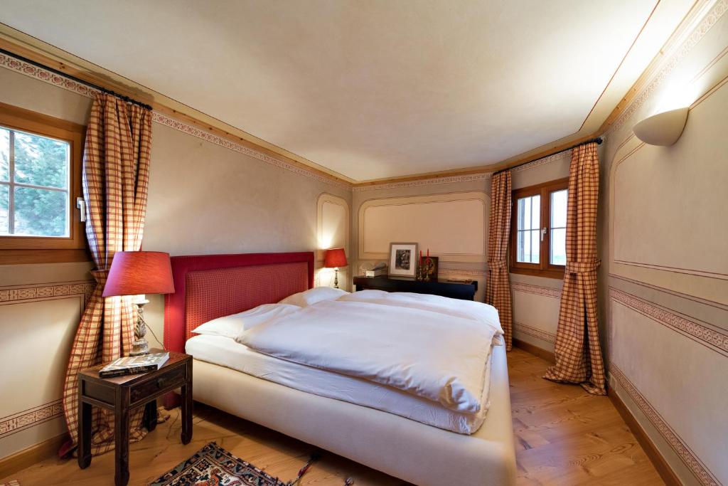 席尔瓦普拉纳Chesa Romana - Silvaplana的一间卧室设有一张大床和两个窗户。