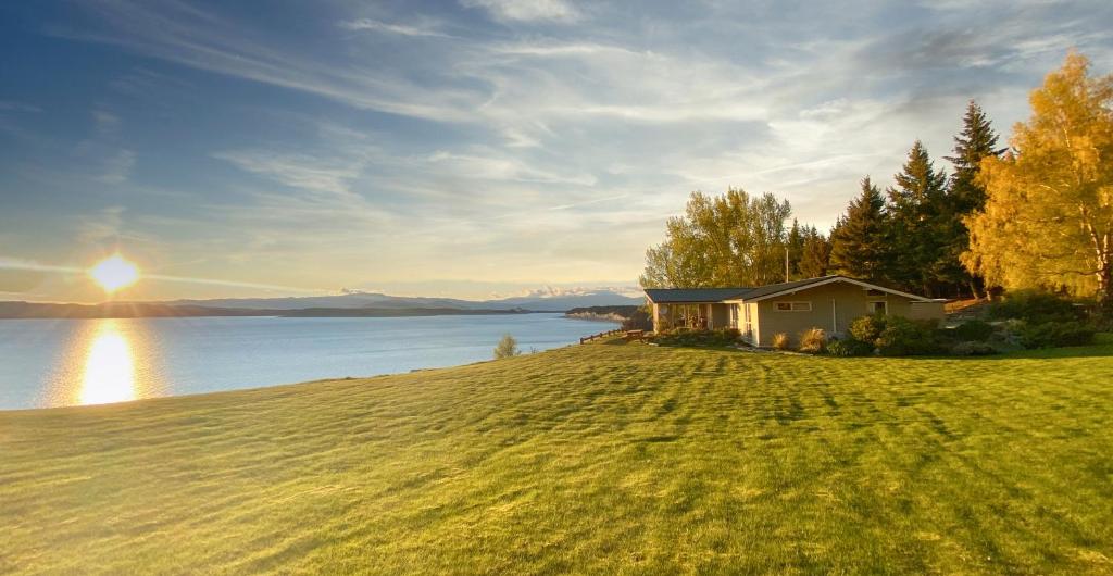 普卡基湖Pukaki Lakeside Getaway NZ的水体旁山丘上的房屋