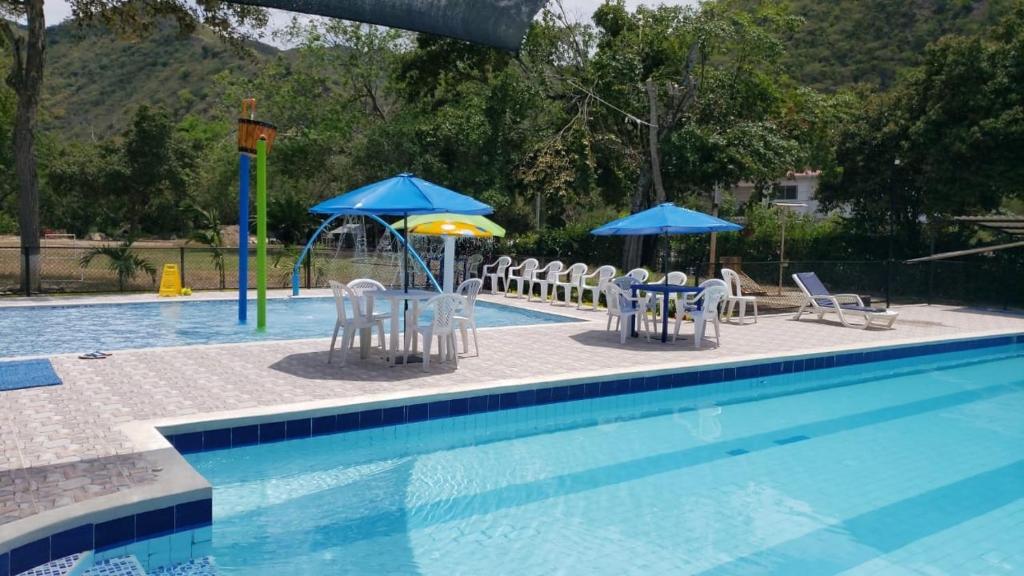 阿普洛Club campestre el Peñón de Apulo的游泳池配有椅子和遮阳伞以及桌椅