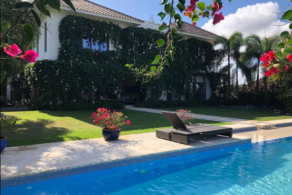 圣地亚哥洛斯卡巴Casa Tropical con Hermosos Atardeceres Caribeños的游泳池旁的长凳上设有膝盖的房子