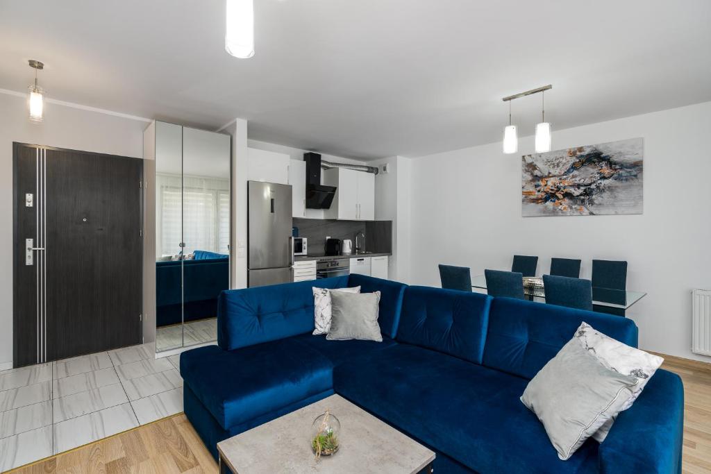 波兹南Sleepway Apartments - Strzelecka 29A-15的一间带蓝色沙发的客厅和一间厨房