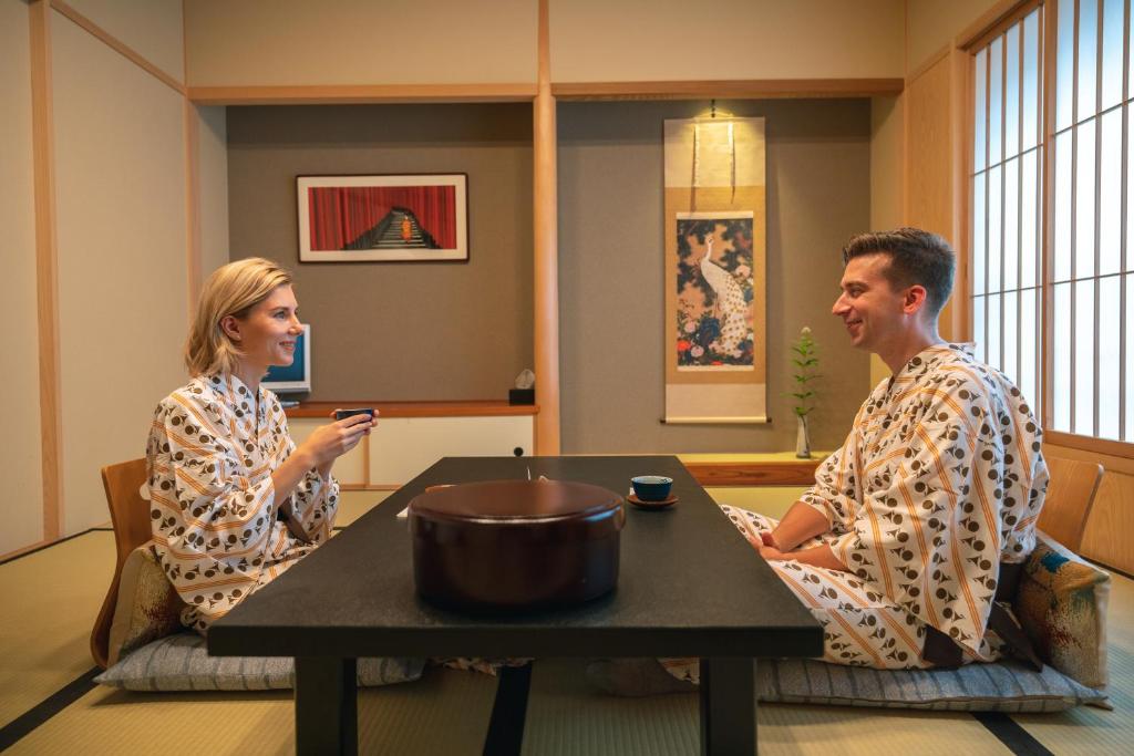 京都Nishiyama Ryokan - Established in 1953的坐在桌子上的男人和女人