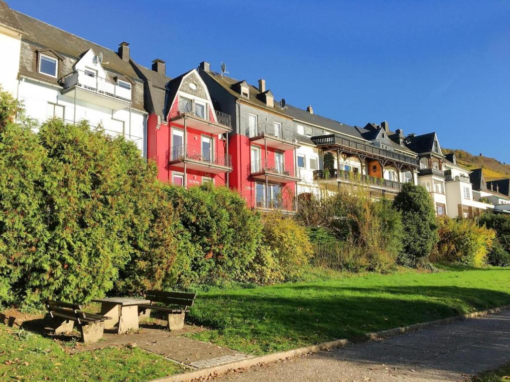 摩泽尔河畔的泽尔Ferienhaus Mosellage的前面有长凳的红色建筑