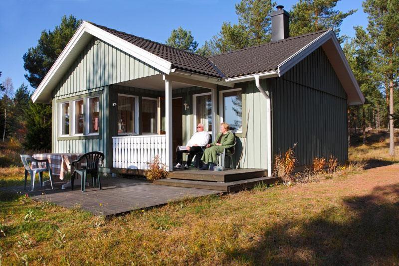 埃克勒Marbyfjärden seaside village Lyckan的两个人坐在一个小房子的门廊上