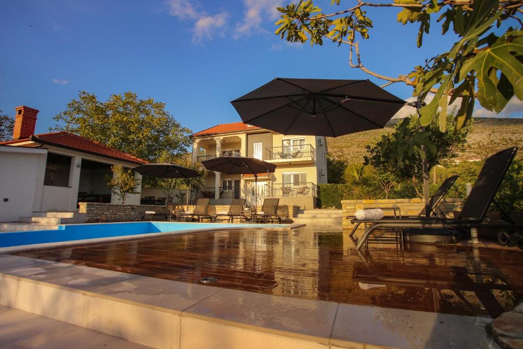 莫斯塔尔Villa Infinity Mostar的一座带遮阳伞的游泳池的房子