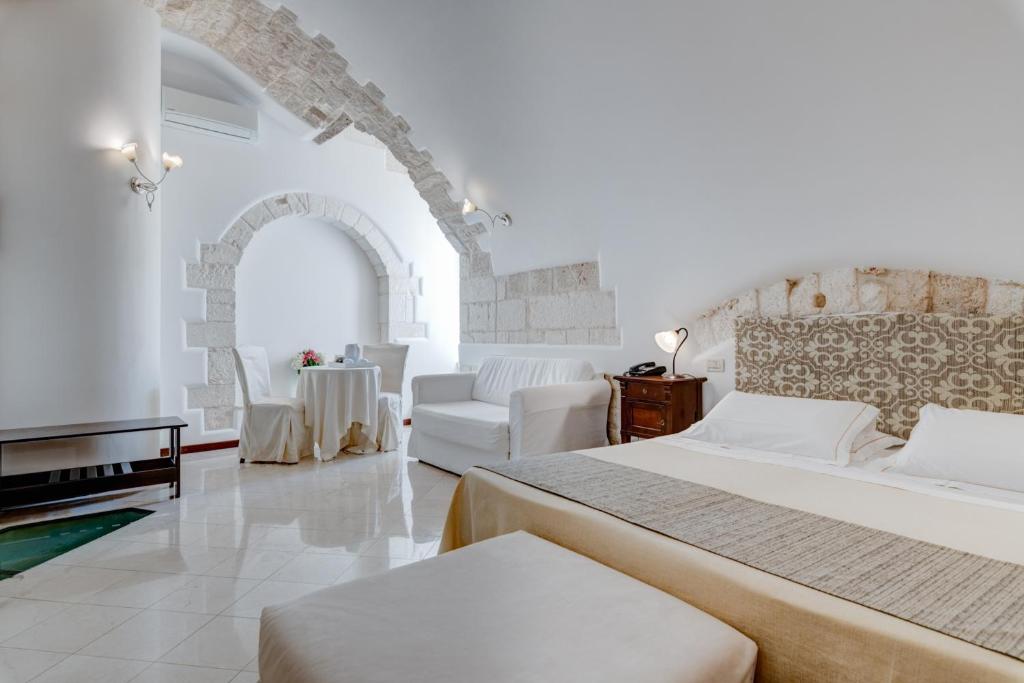 奥斯图尼拉泰拉酒店的一间白色的大房间,配有两张床和一张沙发