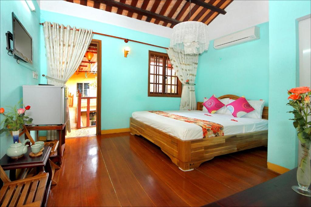 会安芽兰寄宿酒店的卧室拥有蓝色的墙壁,配有一张带粉红色枕头的床。