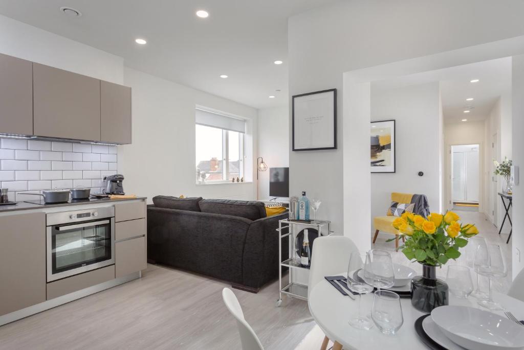 斯蒂夫尼奇Luxury Serviced Apartments Stevenage, Hertfordshire的厨房以及带沙发和桌子的客厅。