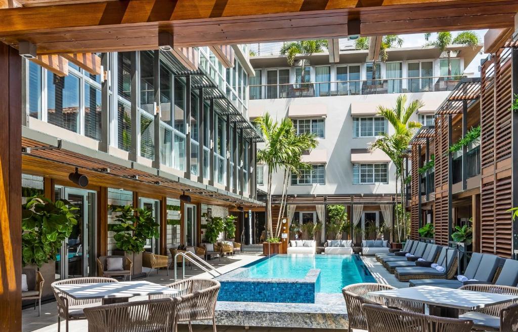 迈阿密海滩Lennox Miami Beach的户外庭院设有游泳池和桌椅