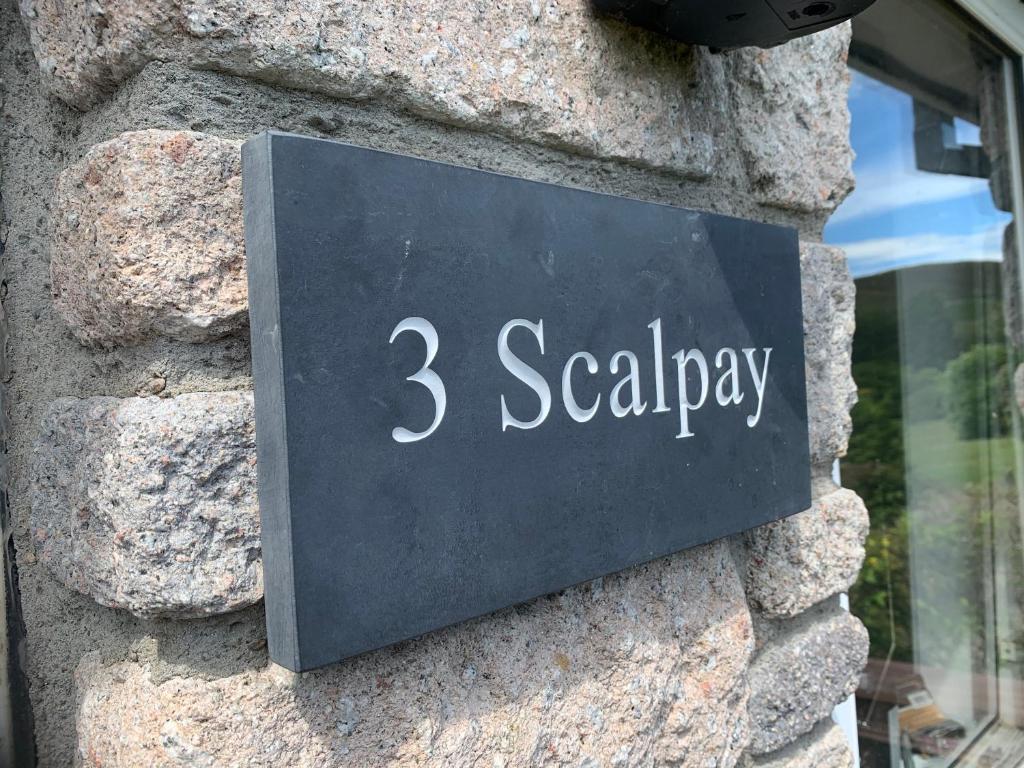 蒂恩格Scalpay@Knock View Apartments, Sleat, Isle of Skye的石墙上的一个标志