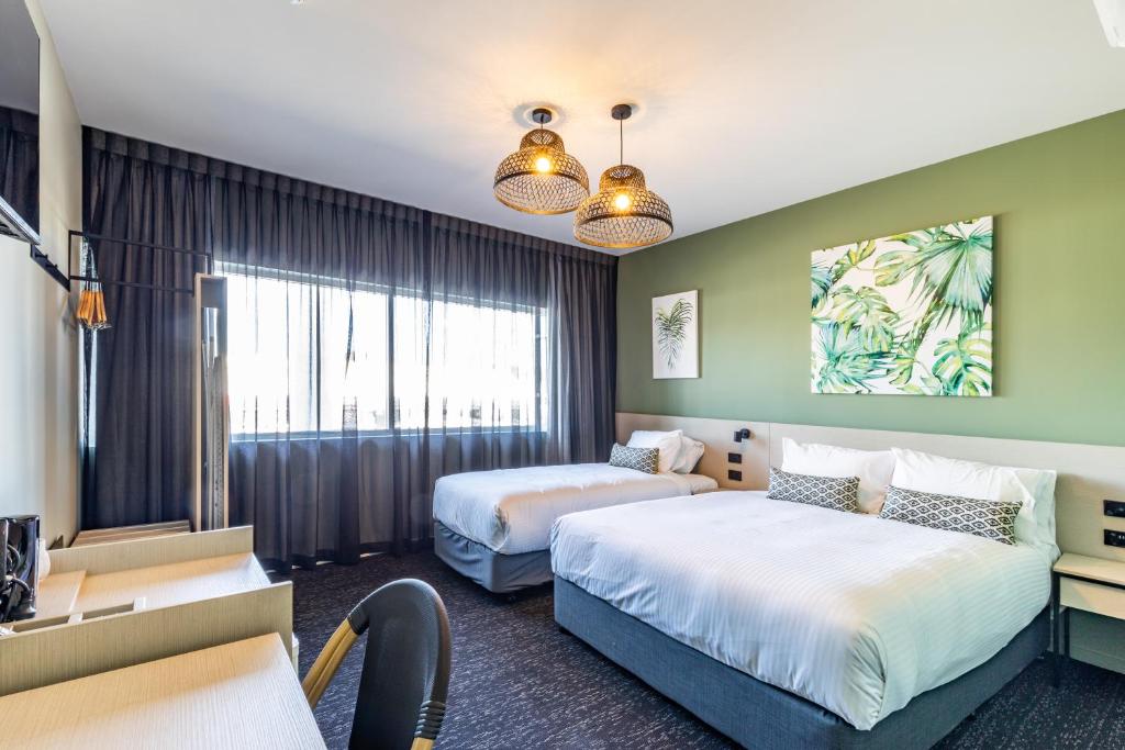 黄金海岸Nightcap at Commercial Hotel的酒店客房配有两张床和一张书桌