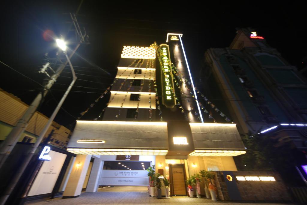 釜山The Stone Bridge Hotel Sasang的一座高大的建筑,有灯光