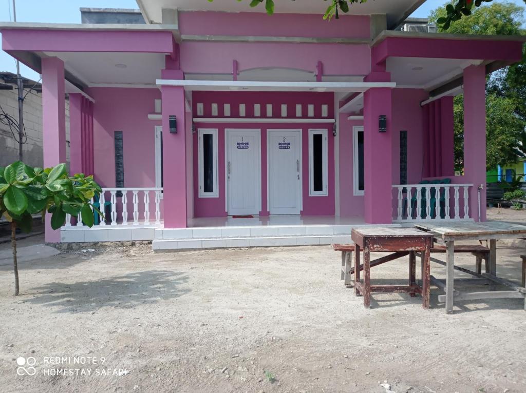 塞里布群岛Homestay safari pulau tidung的粉红色的房子,前面设有野餐桌