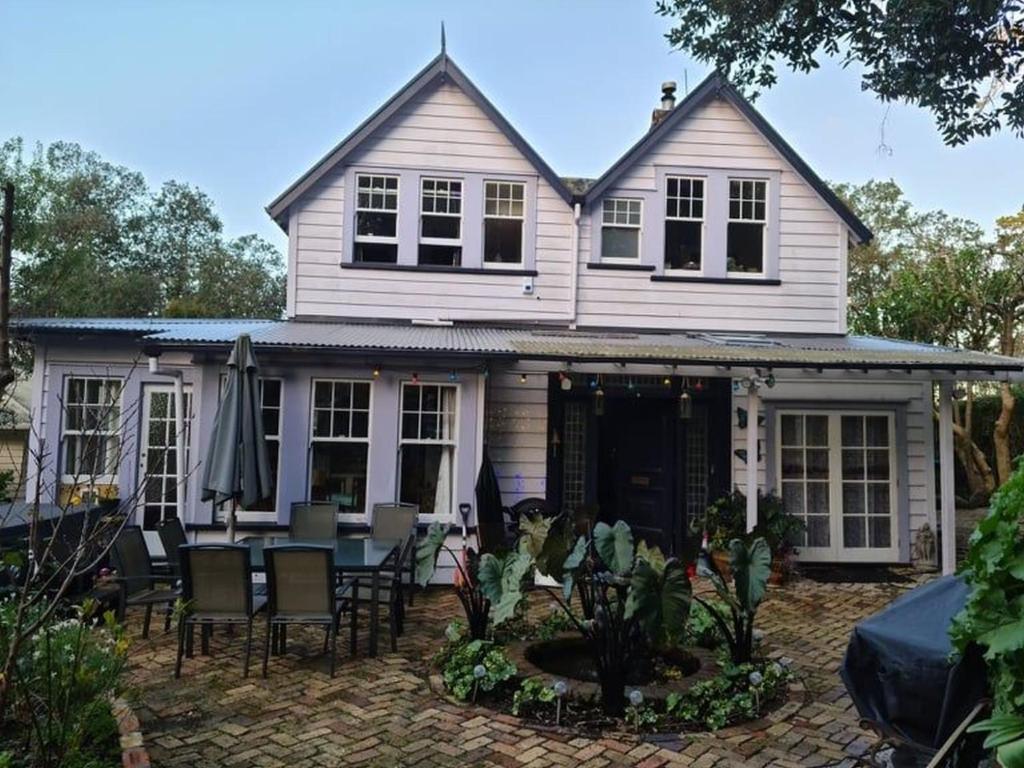 奥克兰Dovecote House的白色的房子设有庭院和桌椅