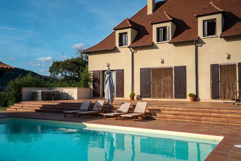 CalèsMaison de Vacances - Domaine de la Couvée的一座房子,设有游泳池、两把椅子和一把遮阳伞