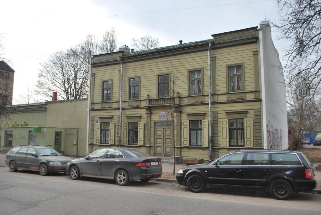 里加Muzeja apartamenti的两辆汽车停在黄色建筑前面