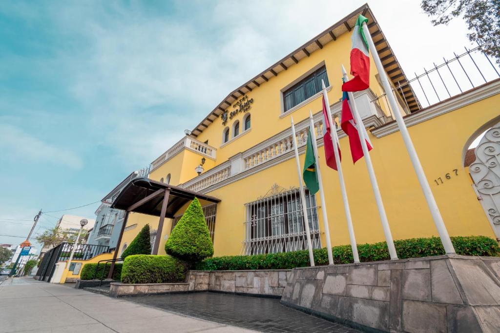 利马Hotel San Isidro Inn的前面有旗帜的黄色建筑