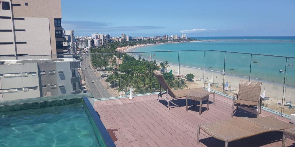 马塞约Pajuçara Front Beach的一个带椅子的阳台、一个游泳池和一个海滩