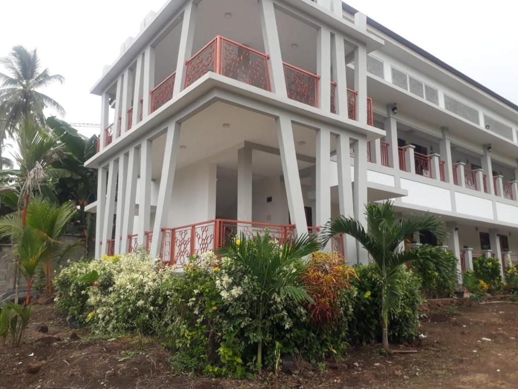 MalalayangKoolKost At Malalayang Manado Minimum Stay 6 Nights的白色的建筑,设有红色的阳台和植物