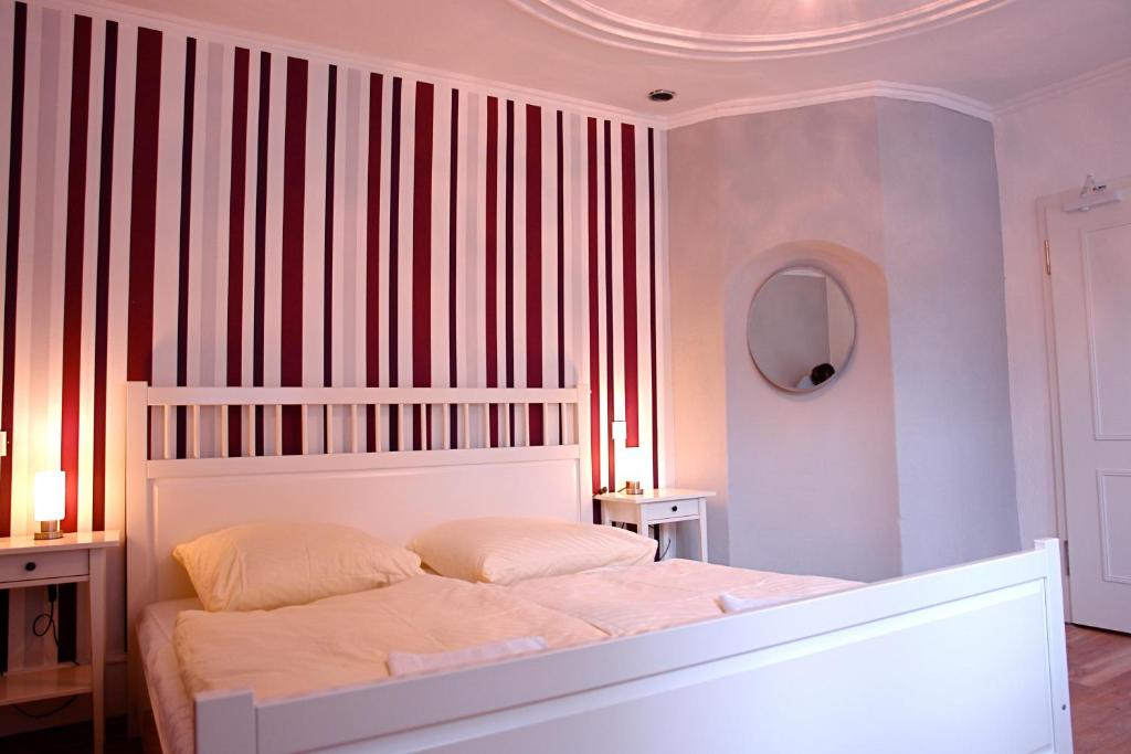 海德堡乐天背包客旅舍的卧室配有白色的床和条纹墙